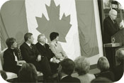 Le President Milliken souligne le Jour du drapeau en toile de fond, le drapeau original qui flottait au haut de la tour de la paix en 1965 