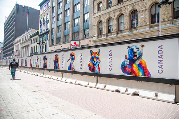 Un trottoir à côté d'un mur de construction. Le mur est orné d'images d'animaux canadiens aux couleurs vives de l'arc-en-ciel.