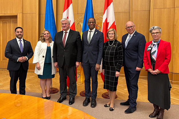 Une délégation de députés de la Chambre des communes en visite en Ukraine, menée par le Président Fergus, pose devant les drapeaux du Canada et de l'Ukraine.