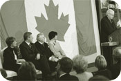 Le President Milliken souligne le Jour du drapeau en toile de fond, le drapeau original qui flottait au haut de la tour de la paix en 1965