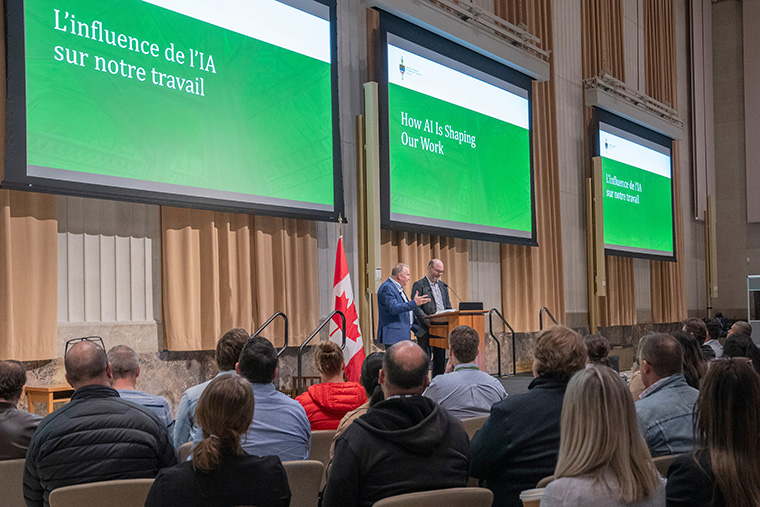 Deux intervenants présentant une diapositive sur « L'influnence de l'IA sur notre travail » à un auditoir