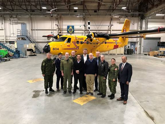 Photo des membres du Comité des affaires étrangères en compagnie de membres de la Force opérationnelle interarmées des Forces armées canadiennes dans un hangar aérien du 440e Escadron de transport à Yellowknife.